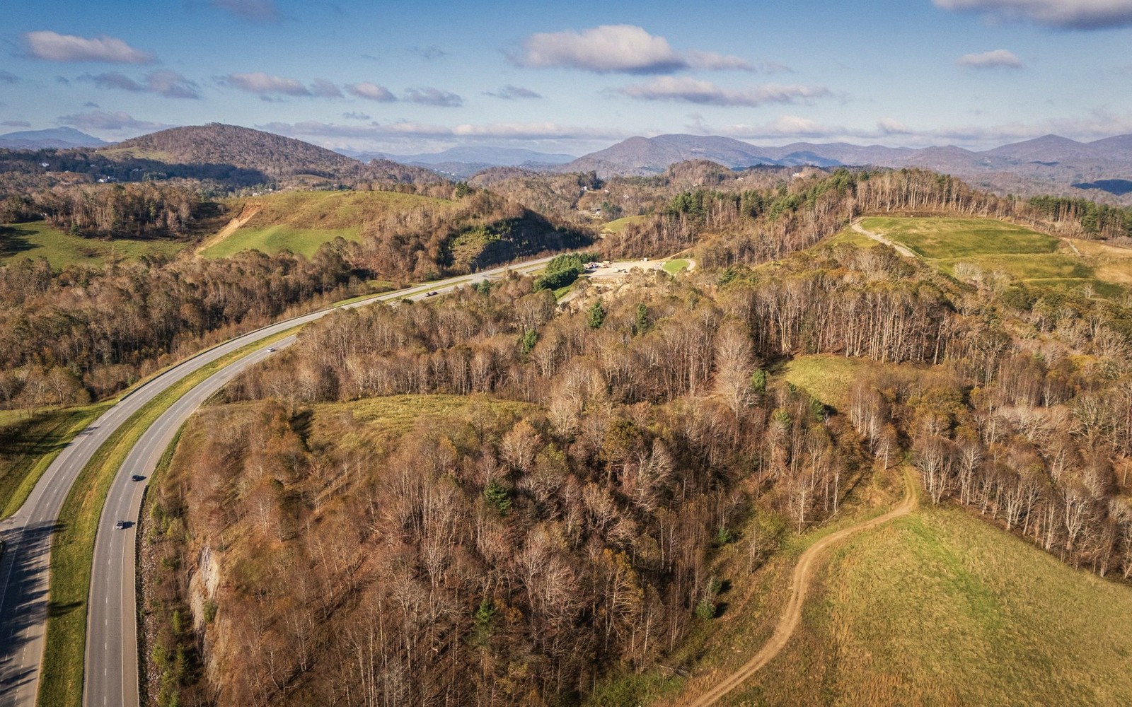 Aerial view of a curving highway winding through wooded hills and pastureland